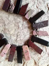 Collar corto elaborado con piedras naturales de rodocrosita, obsidiana y jaspe en tonos rosa, vino, marrón y negro, unidas con cuentas pequeñas.