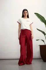 Pantalón de corte amplio y tiro alto, confeccionado en tela con textura tipo lino. Presenta un diseño envolvente en la cintura con un lazo lateral para anudar, creando un efecto de superposición frontal.