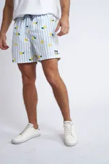 Short de baño con cintura elástica y cordón ajustable, confeccionado en tela ligera de secado rápido. Presenta un estampado botánico integral en tonos amarillos, blancos y azules, con dos bolsillos delanteros y uno posterior.
