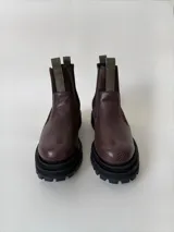 Botas tipo chelsea de cuero, combinando texturas en color bordó. Presentan paneles laterales elásticos en negro, suela track robusta y tiradores en la parte superior.