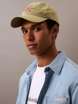 Gorra verde oliva de algodón con visera curva y logo de Calvin Klein Jeans bordado en el frente en color rojo y azul. Ajuste trasero con hebilla metálica.