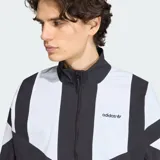 Campera deportiva Adidas Blocked de diseño bicolor en negro y blanco, con cuello alto, cierre frontal y bolsillos laterales. Presenta el logo del Trifolio bordado en el pecho.