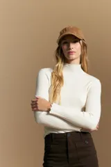 Polera de tejido acanalado con cuello alto, corte ajustado al cuerpo y mangas tres cuartos con terminaciones onduladas en los puños.