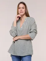 Blusa de silueta holgada a rayas verdes y blancas, confeccionada en tela liviana con textura arrugada. Presenta cuello en V profundo con botones frontales, mangas 3/4 de hombro caído y ruedo asimétrico con aberturas laterales.