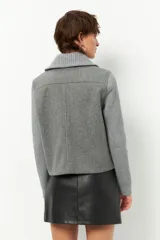 Tapado corto negro de paño con mangas y cuello tejidos, cierre metálico y bolsillos.