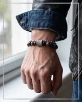 Pulsera doble de acero inoxidable con piedras naturales de ónix negro y piedras jaspeadas en tonos tierra, unidas por un cierre cilíndrico metálico con textura estriada.