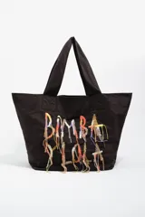 Bolso tipo shopper de color negro, confeccionado en tejido técnico, con doble asa de hombro y detalle de bordado decorativo con hilos colgantes multicolor en el frente.