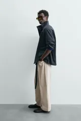 Parka de corte relajado confeccionada en tejido de algodón con efecto lavado. Presenta cuello subido, manga larga con puños abotonados, bolsillos frontales de plastrón con solapa y cintura ajustable mediante cordón interior. El cierre frontal es de cremallera oculta por una solapa con botones a presión.