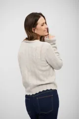 Buzo de tejido de punto en color gris claro, con diseño de textura acanalada vertical y terminaciones onduladas en cuello, puños y ruedo.