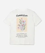 Remera de algodón color blanco crudo, manga corta y cuello redondo, con un pequeño estampado floral y lettering en el área del pecho.