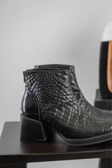 Conjunto de dos piezas compuesto por una musculosa de cuello redondo y un pantalón de corte recto, ambos en color negro. El pantalón incluye un cinturón ancho con hebilla metálica circular.