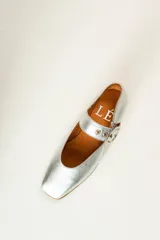 Zapato bajo de gamuza color beige con correa sobre el empeine y hebilla dorada.