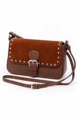 Bolso tipo cartera de mano color marrón, confeccionado en cuerina y gamuza, con solapa frontal decorada con tachas metálicas plateadas y una tira con hebilla central. Cuenta con un asa corta para llevar al hombro.