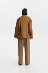 Chaqueta corta estilo sobretodo, color marrón, con silueta amplia, cuello solapa ancho, cierre cruzado con botones oscuros y hombreras.