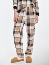 Pantalón de dormir de tela fleece con estampado de cuadros en tonos beige, blanco y negro. Presenta un corte recto y holgado con puños elásticos en los tobillos.
