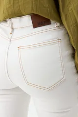 Jean flare de color blanco con costuras en contraste y diseño de tiro medio.
