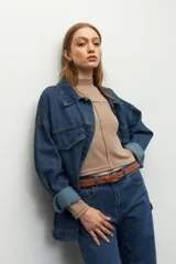 Polera blanca de manga larga con cuello alto y costuras cruzadas a la vista en el frente.