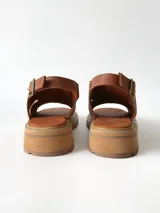 Sandalias de cuero combinadas en color marrón y crudo, con suela track y taco bajo. Tienen tira ajustable con hebilla en el talón.