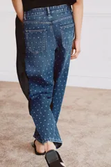 Jeans de tiro medio con corte tapered y largo al tobillo. Presenta un diseño de cinco bolsillos, cierre frontal con cremallera y botón, y un estampado de lunares a contraste sobre un tejido denim con efecto lavado.
