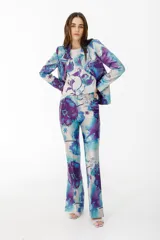 Pantalón de vestir con leve evasé y tajo en laterales, con estampado de flores grandes en tonos violeta y naranja.