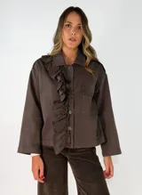 Chaqueta color chocolate con diseño de volados en el frente, cuello camisero, cierre frontal con botones y bolsillo lateral en el pecho.