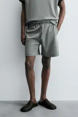 Bermuda de algodón color beige claro, corte relajado (relaxed fit), con cintura elástica ajustable mediante cordón y bolsillos laterales y trasero de plastrón.