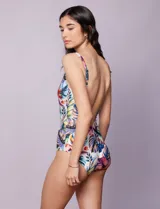 Malla enteriza con escote en V cruzado y breteles finos regulables, confeccionada en tejido estampado con diseño tropical y floral en tonos blancos, fucsias, azules y verdes.