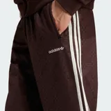 Pantalón deportivo Adidas color marrón, con diseño de monograma grabado en relieve en todo el tejido, franjas laterales blancas y el logo de la marca bordado en la cadera.