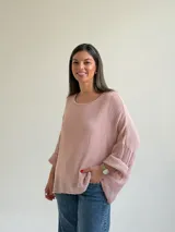 Sweater de punto en color rosado, con diseño holgado, cuello redondo y mangas murciélago anchas con vuelta.