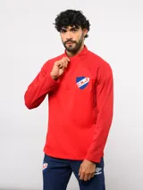 Buzo de entrenamiento Umbro del Club Nacional de Football, con medio cierre frontal, cuello alto y mangas largas. Presenta el logo de la marca y el escudo del club en el pecho.