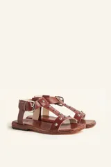 Sandalias negras de cuero con tiras finas, pulsera al tobillo con hebilla metálica y apliques de tachas plateadas.