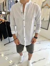 Camisa de lino blanca con finas rayas negras, cuello mao y cierre frontal con botones de madera.