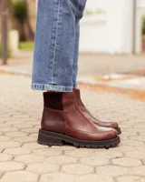 Botinetas de cuero color chocolate con diseño de paneles combinados en cuero liso y cuero texturizado. Presentan una suela track gruesa de goma negra y un corte tipo chelsea.