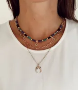 Set de collares tipo cascada en color dorado, compuesto por tres niveles: una gargantilla de cuentas multicolor con dijes de estrellas, una cadena de eslabones y una cadena fina con dije de medialuna.