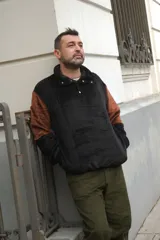 Buzo negro con mangas marrones, cuello alto con botones a presión y corte holgado.