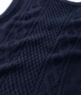Chaleco de punto sin mangas con escote en V y aberturas laterales. Presenta una textura de tejido trenzado y un corte alargado, ideal para superposiciones.