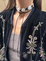 Gargantilla negra con apliques de flores doradas y tiras para atar.