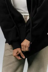 Campera deportiva con capucha de corte oversize, confeccionada en tejido suave con interior forrado en piel sintética. Presenta cierre frontal completo, bolsillos laterales y capucha amplia con cordones largos ajustables.