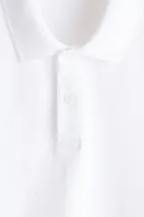 Remera polo blanca de manga corta en piqué de algodón, con cuello clásico y tapeta de dos botones.