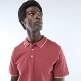 Remera polo de piqué de algodón color rojo, con cuello y puños acanalados en contraste blanco, y cierre frontal de tres botones.