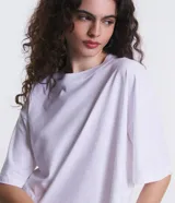 Remera cropped de manga corta, cuello redondo y calce oversized, confeccionada en tejido de algodón tipo media malla.