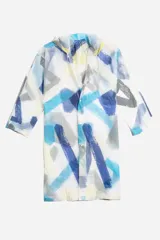 Piloto impermeable de corte recto y largo midi, con capucha ajustable mediante cordones. Presenta un diseño estampado con motivos botánicos en tonos verdes y amarillos sobre una base translúcida. Cuenta con cierre frontal mediante botones a presión y mangas largas.