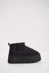 Bota corta tipo ugg de color negro, con plataforma alta y suela dentada. Presenta costuras reforzadas y tirador en la parte trasera.