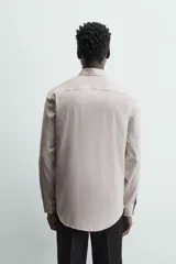 Camisa de hombre color beige claro, de corte slim fit, con cuello italiano, manga larga y cierre frontal de botonadura.