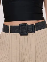 Pantalón wide leg blanco con finas rayas verticales oscuras, tiro alto, bolsillos laterales y pinzas frontales. Incluye un cinturón trenzado de rafia con hebilla rectangular.
