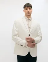Blazer de medio forro color beige, confeccionado en mezcla de algodón y lino. Presenta una silueta estructurada con solapas de muesca, cierre frontal de un botón y bolsillos con solapa.