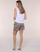 Blusa blanca sin mangas, confeccionada en algodón con sutiles rayas verticales en relieve. Presenta cuello redondo, cierre frontal con botones de madera y un nudo ajustable en el dobladillo delantero.