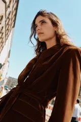 Blazer de terciopelo color marrón, con cuello solapa, manga larga y cierre frontal cruzado con botones. Incluye bolsillos con solapa en el delantero y un cinturón del mismo tejido para ajustar a la cintura.
