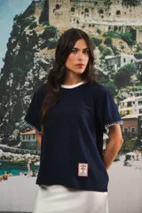 Remera de algodón color azul marino, corte relajado con hombro caído. Presenta cuello redondo blanco y bordado a mano en contraste en los puños de las mangas. Tiene un parche bordado en la parte inferior del frente.