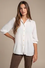 Blusa blanca oversize de manga 3/4, con cuello camisero y cierre frontal de botones.